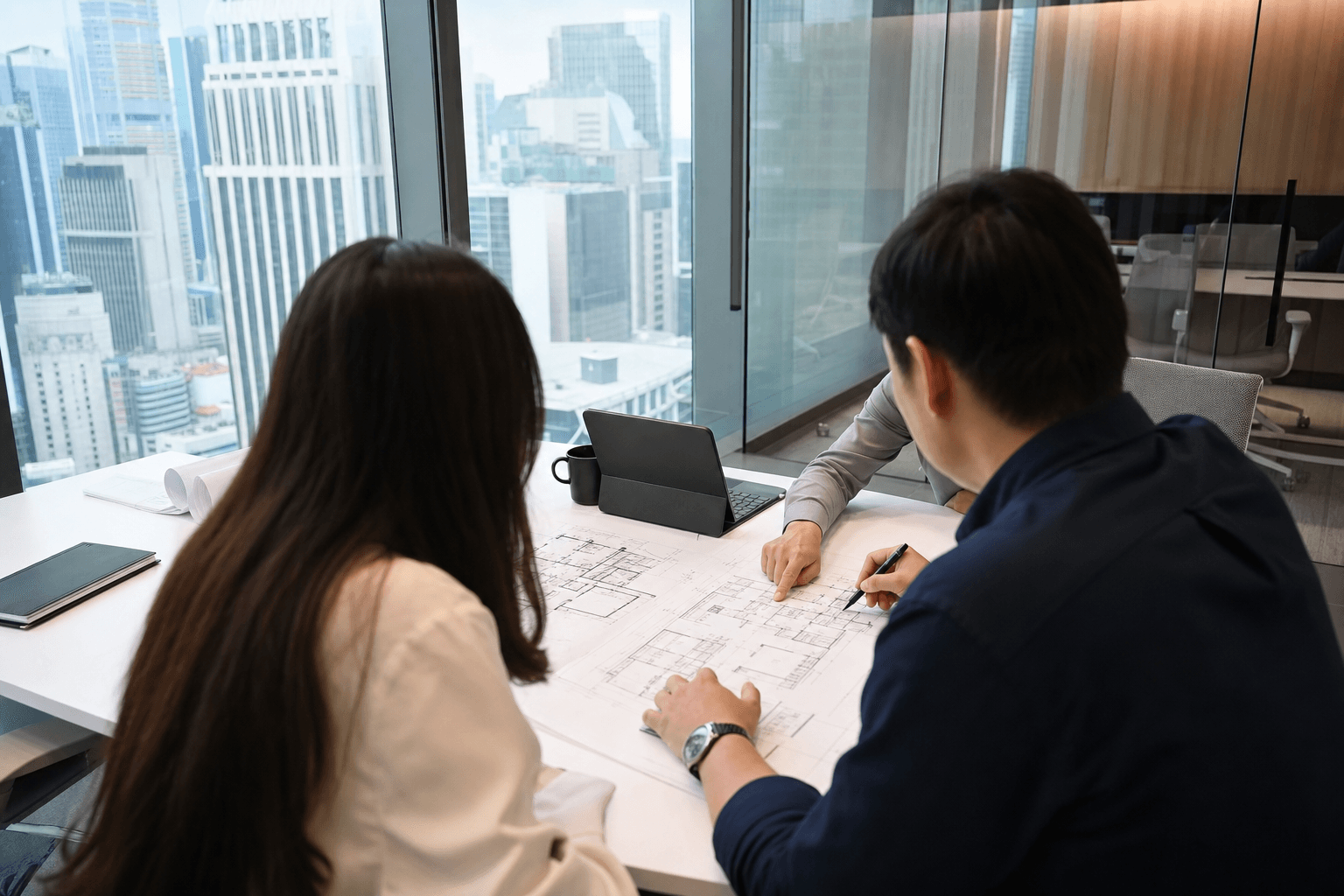 Singapore office fit-out planning meeting with floor plans on a conference table in a glass meeting room
