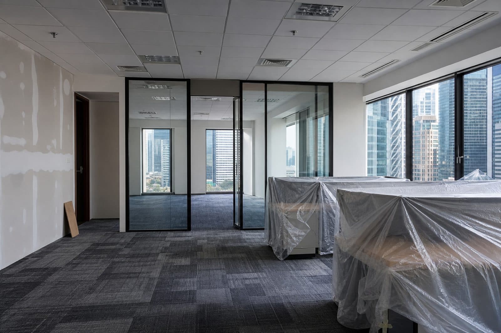 Singapore fitted office mid-renovation with glass partition frames and protective sheets on the floor