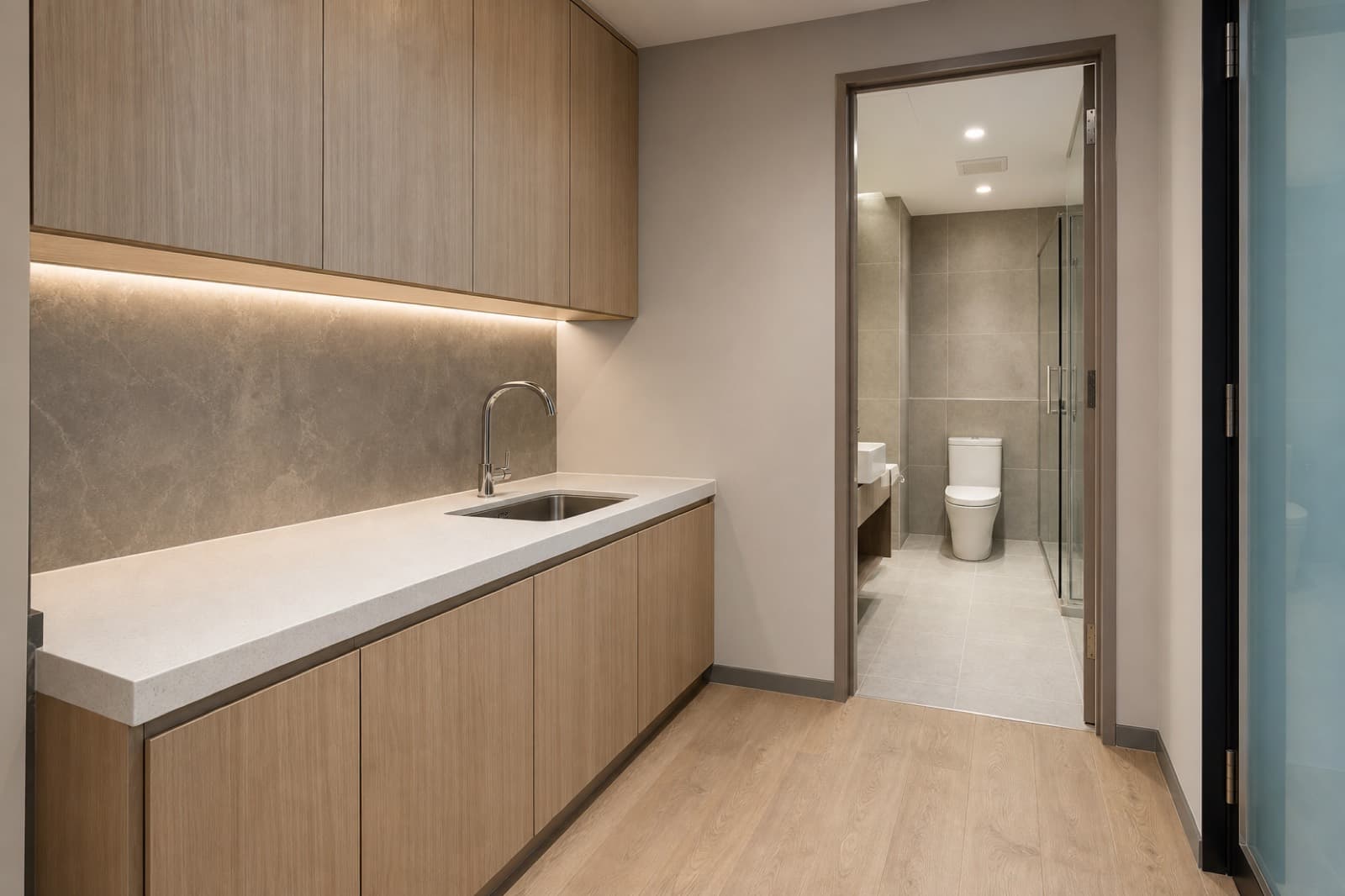 Renovated Singapore office pantry with quartz counter beside a clean commercial washroom entrance