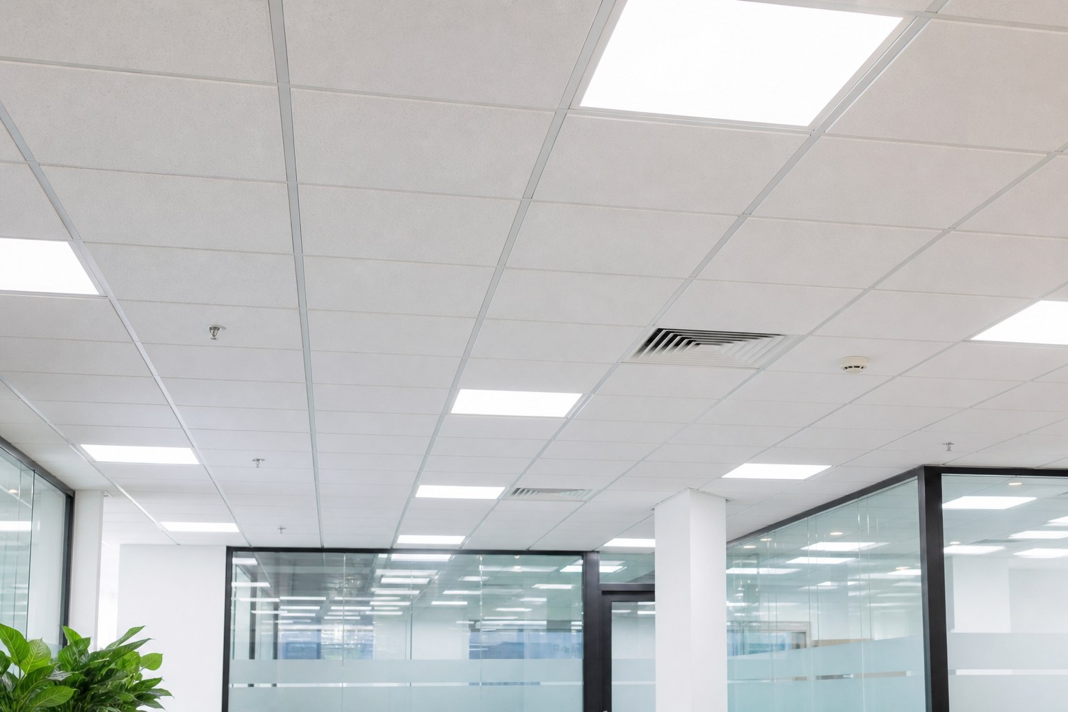 White suspended ceiling grid with recessed LED panels in a Singapore office