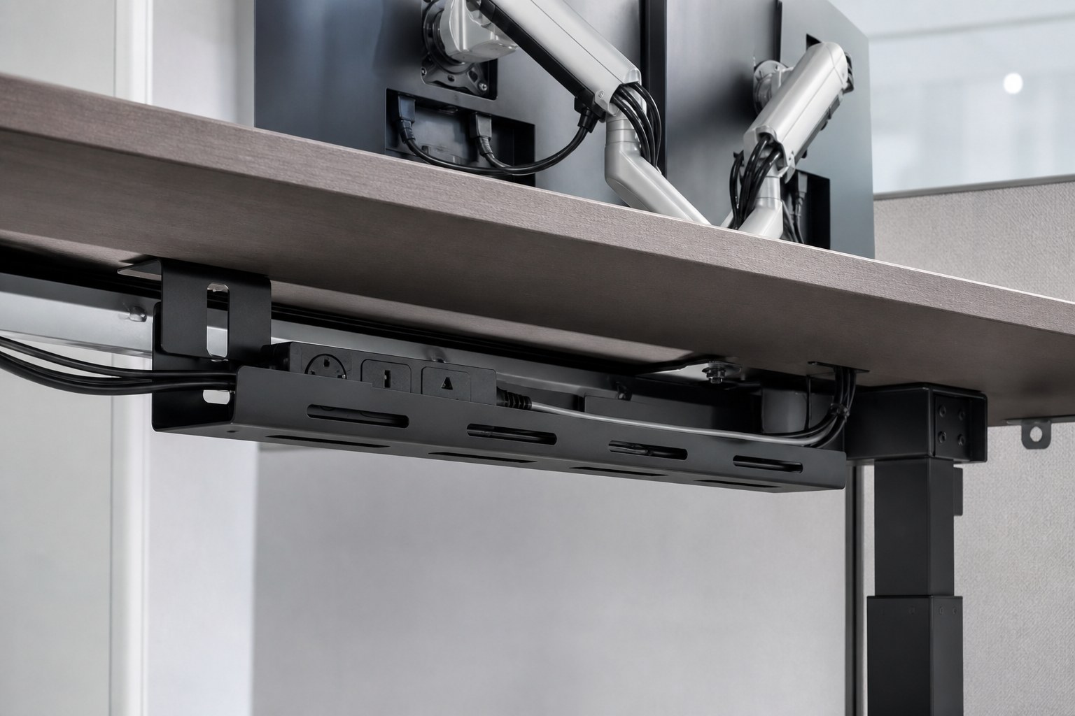 Under-desk cable tray and power sockets on a sit-stand workstation
